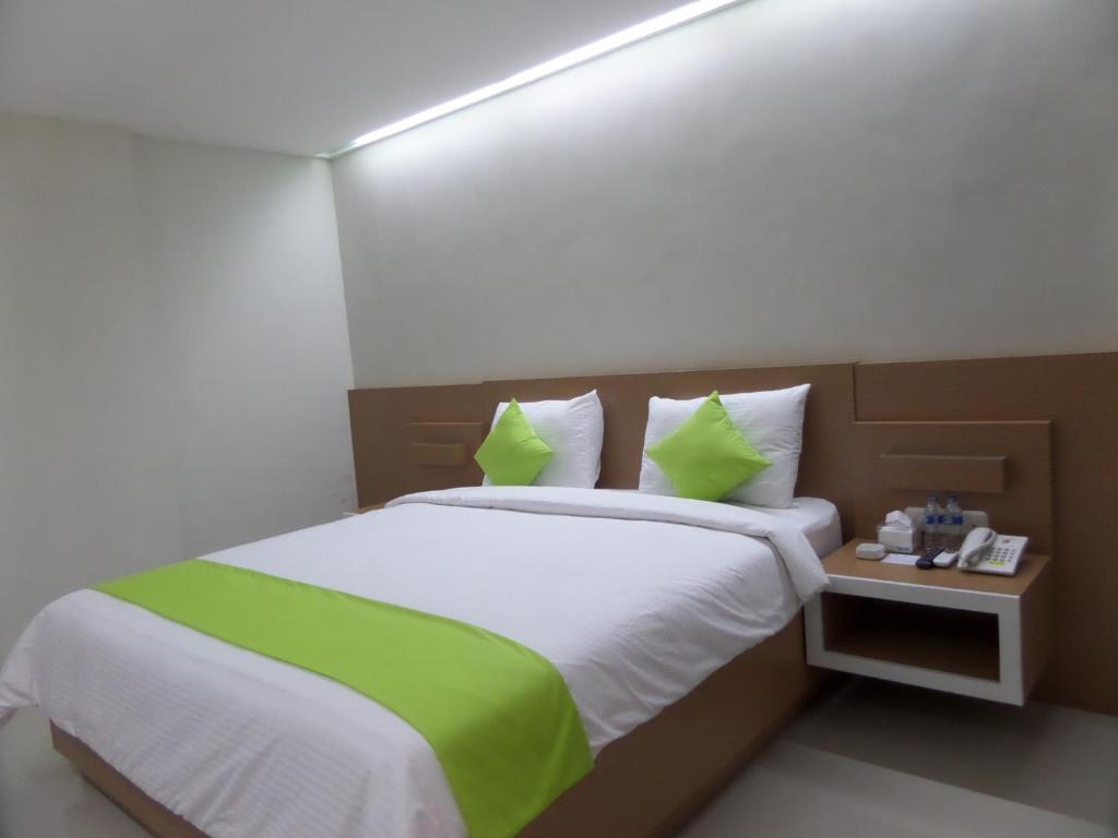 玛琅辛塔旅馆的一间卧室配有一张带绿色枕头的大床