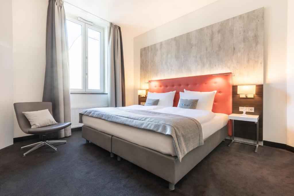 柏林Select Hotel Berlin The Wall - Apartments的一间卧室配有一张大床和一把椅子