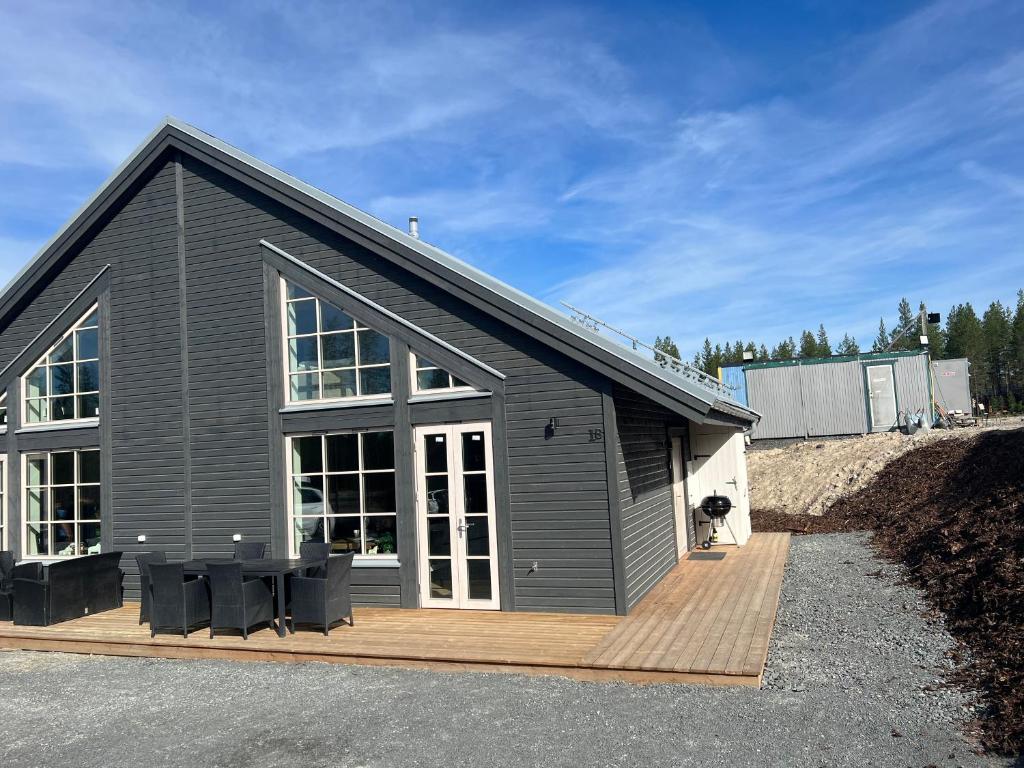 伊德勒New cabin in fabulous Idre activity area的灰色的房子,配有带黑色椅子的木制甲板