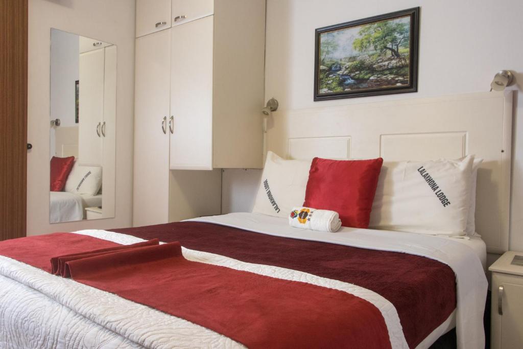 Umzimkulu拉拉虹那山林小屋的一间卧室配有一张带红色和白色枕头的大床