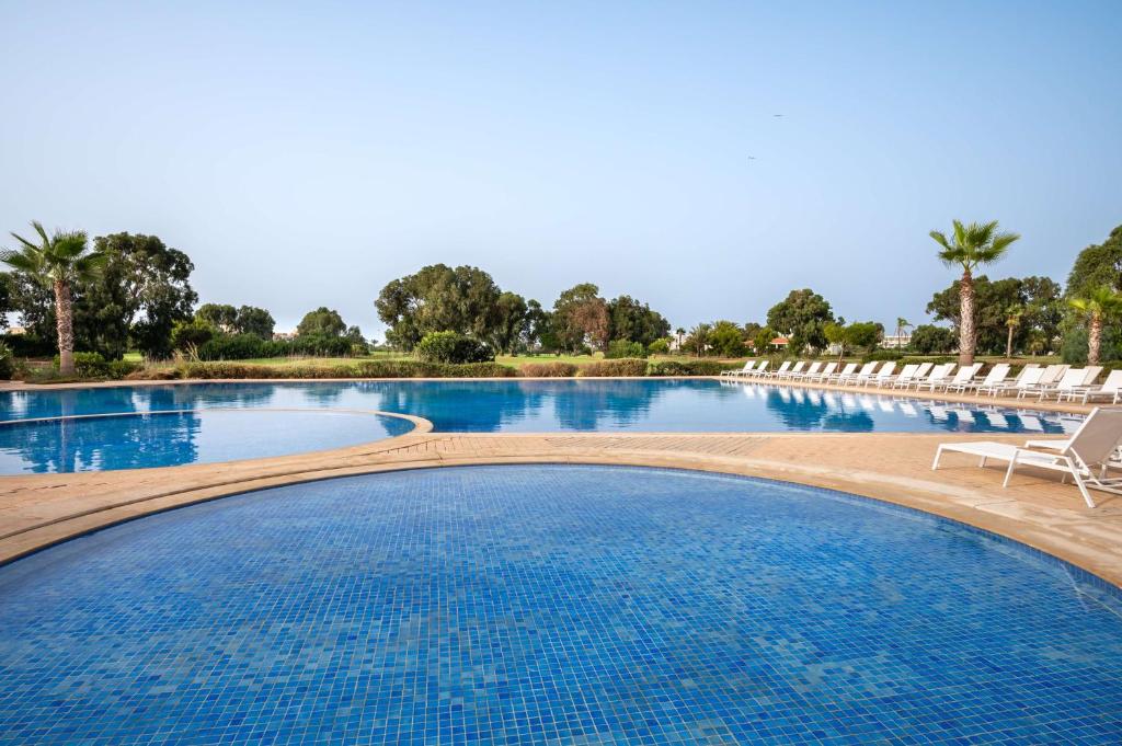 萨伊迪耶Radisson Blu Resort, Saidia Garden的一个带椅子和蓝色水的大型游泳池
