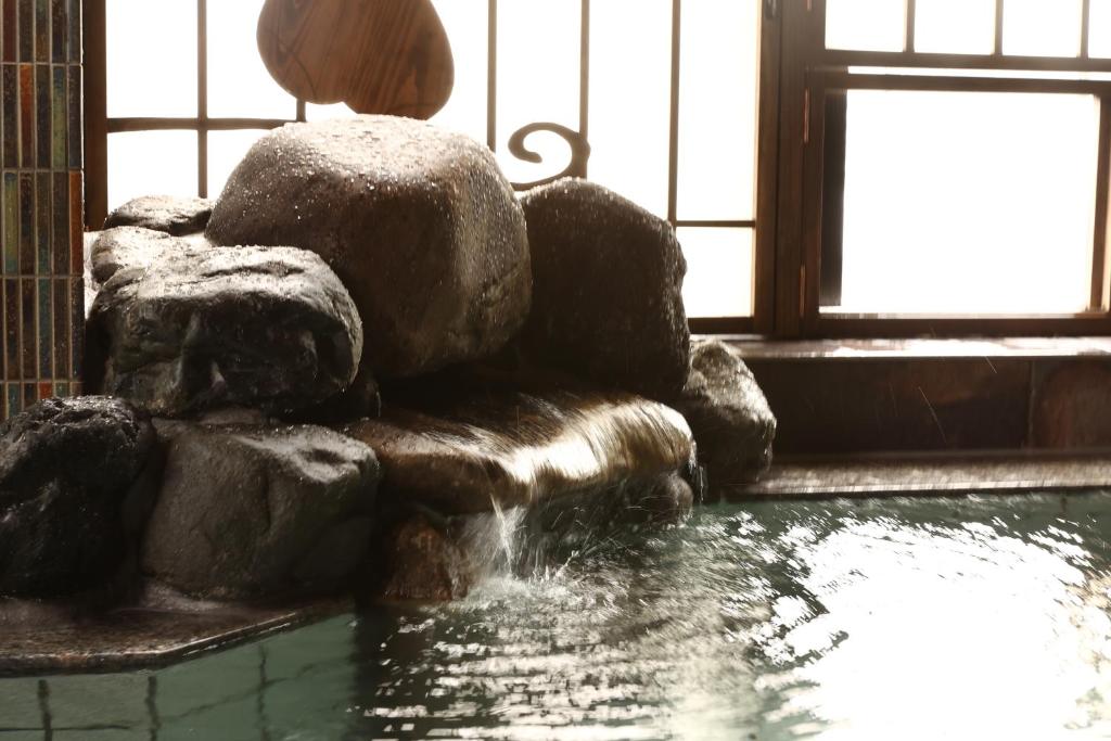 冈山Dormy Inn Okayama Natural Hot Spring的喷泉,位于一个岩石和窗户的房间