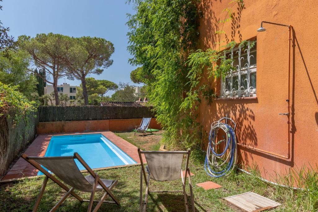 帕拉弗鲁赫尔Illes Medes a el Golfet的一个带游泳池和两把椅子的庭院和一座建筑