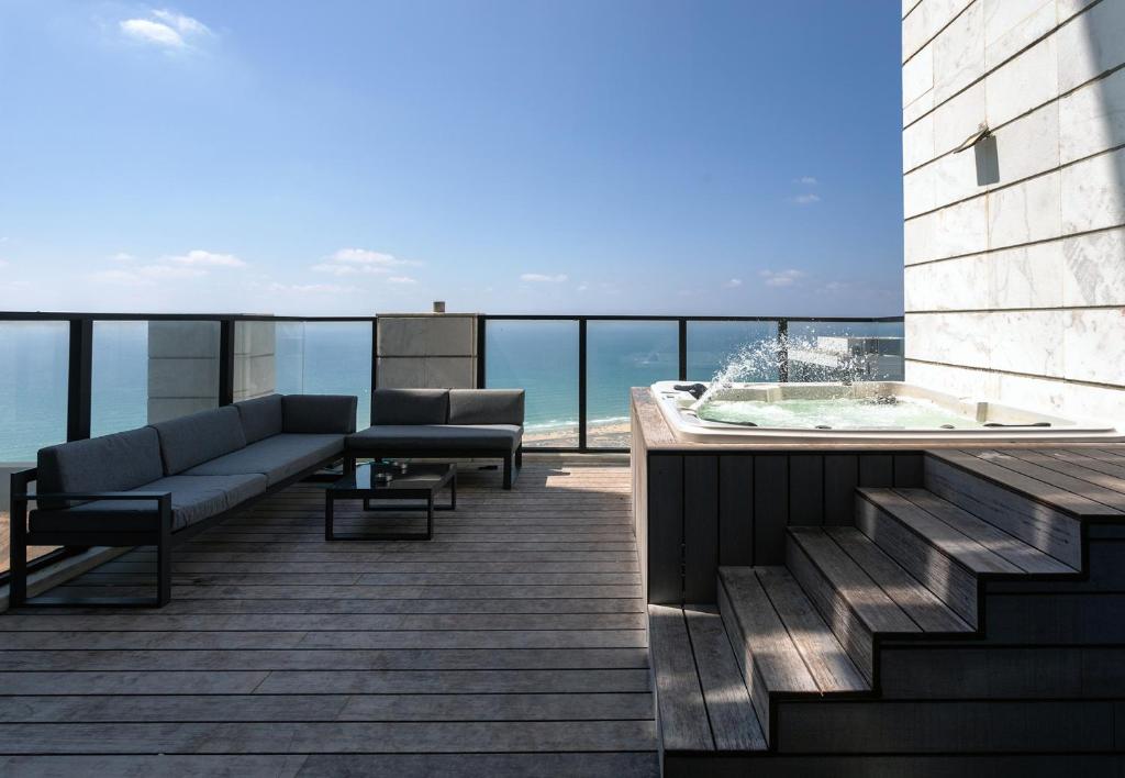 巴特亚姆YalaRent sea-breeze penthouse with jacuzzi的大楼内的阳台配有沙发和热水浴池。
