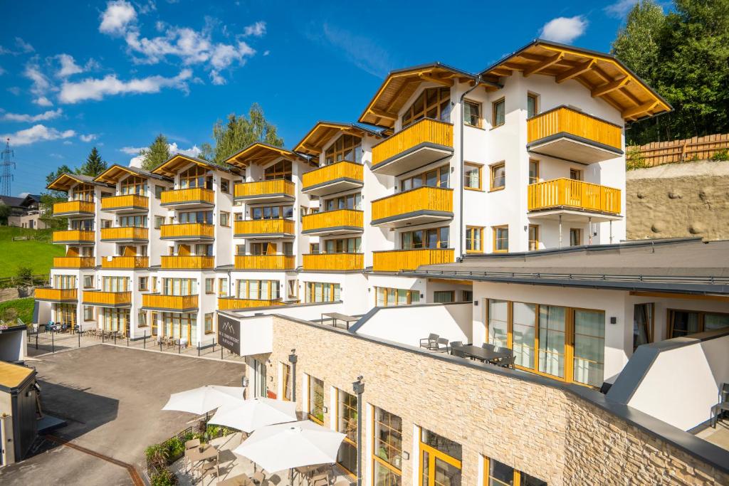 蓬高圣约翰Ski- & Sonnenresort Alpendorf by AlpenTravel的公寓大楼设有橙色阳台和停车场