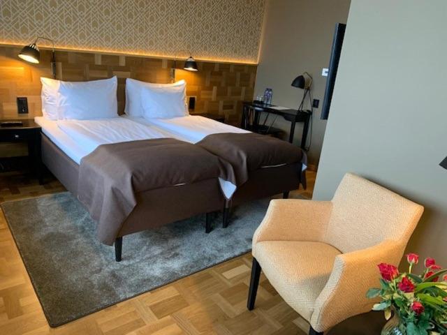 尼布鲁Nybro Stora Hotellet的一间卧室配有一张大床和一把椅子