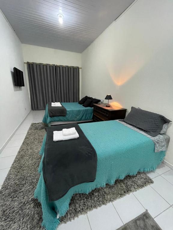 坎波斯杜若尔当Kitnets da Lane的一间卧室配有两张床、一张桌子和一台电视。
