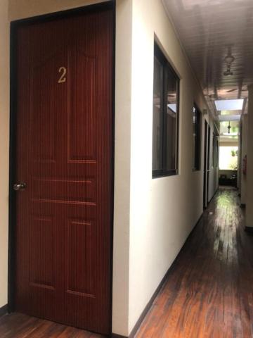 阿拉胡埃拉#2 private room close to airport的走廊设有棕色的门,走廊设有白色墙壁
