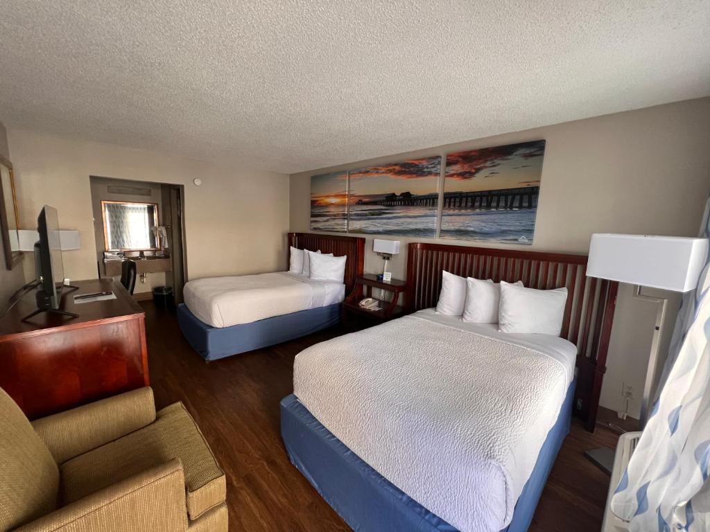 代托纳海滩Days Inn by Wyndham Daytona Beach Speedway的酒店客房,设有两张床和一张沙发