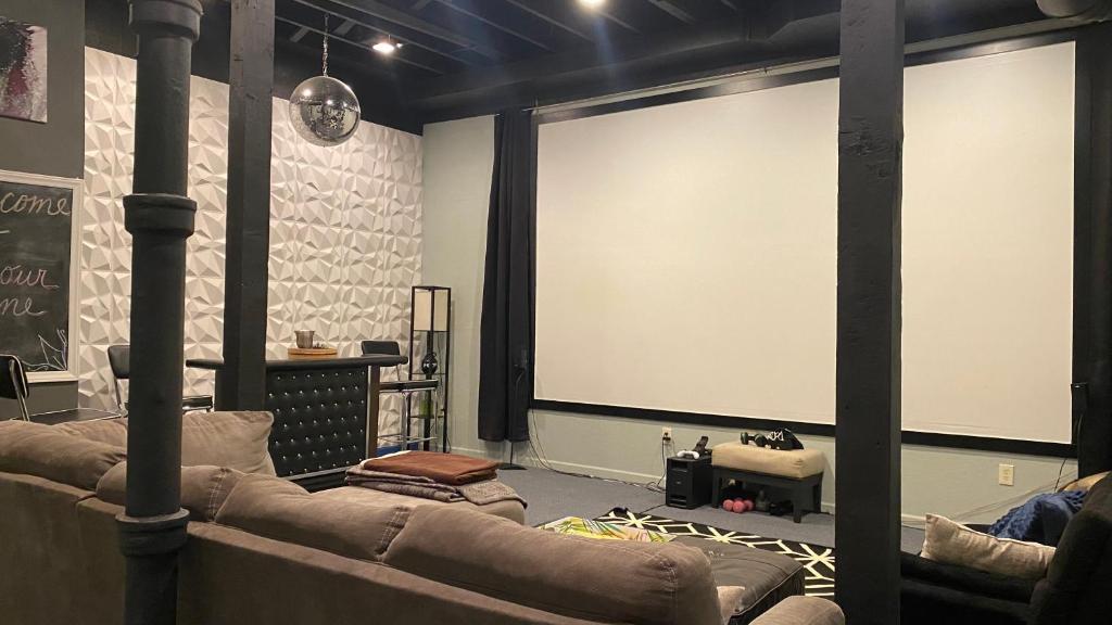 奥马哈160inch Home Movie Theater- Great for movie night!的一间设有两张沙发和一个大投影屏幕的房间