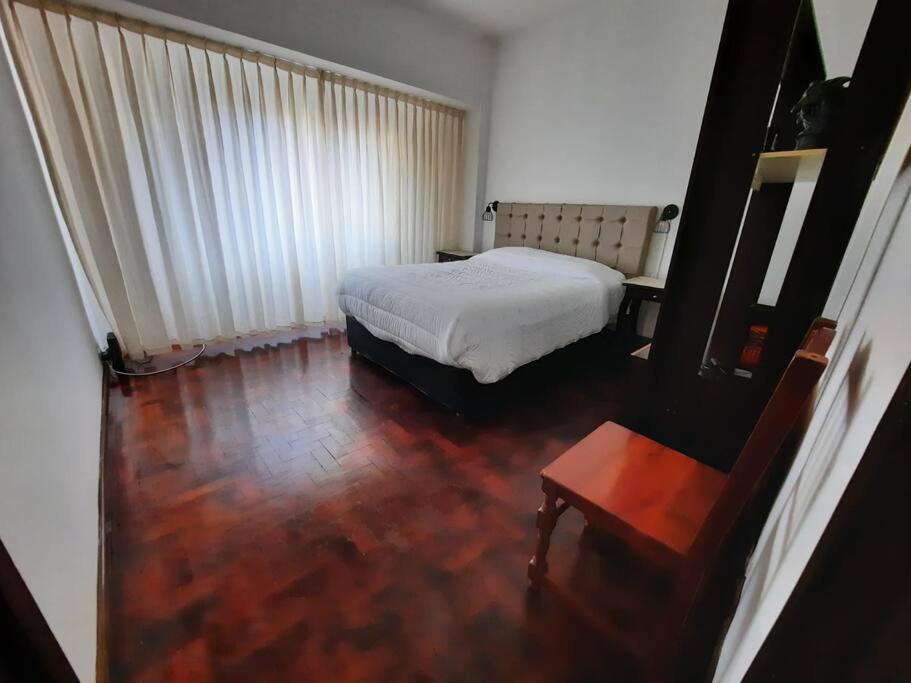 科尔多瓦Hermoso Departamento centrico的卧室配有白色的床,铺有木地板
