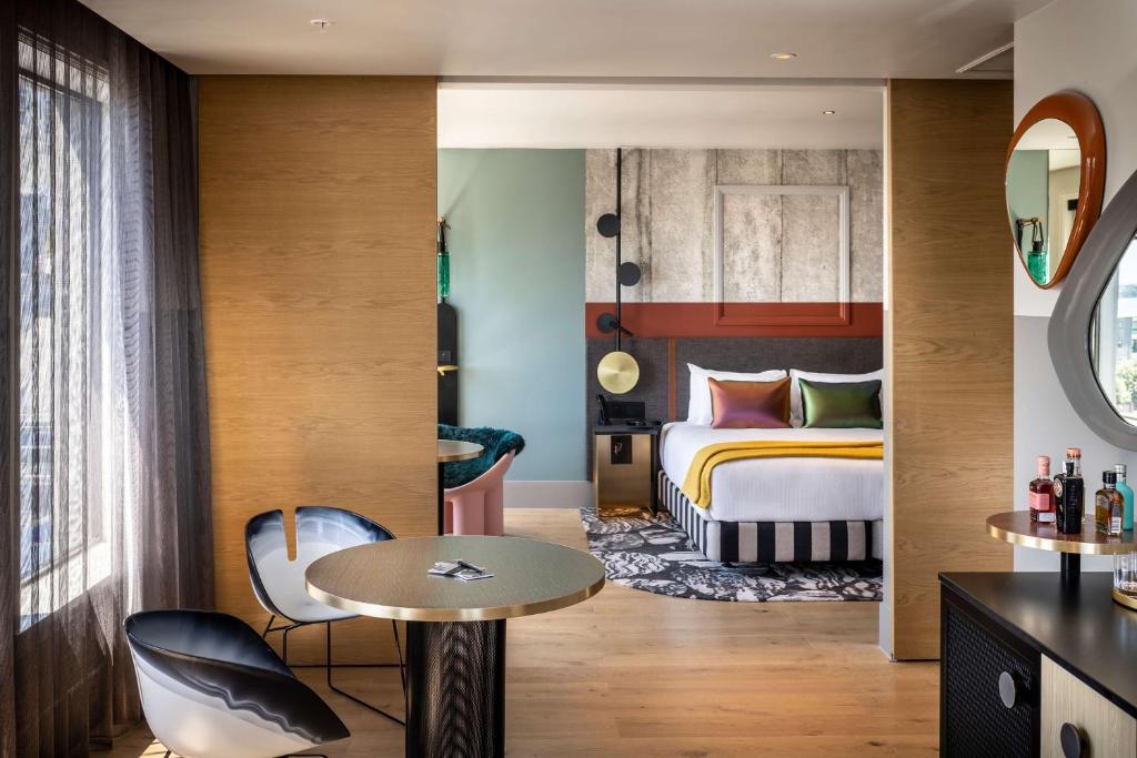 奥克兰QT Auckland的酒店客房带一张床、一张桌子和椅子