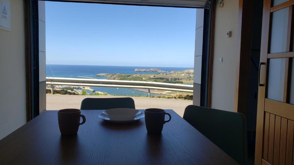 苏安塞斯La Casuca de Rosi en Suances的一张桌子,带两个杯子,享有海景