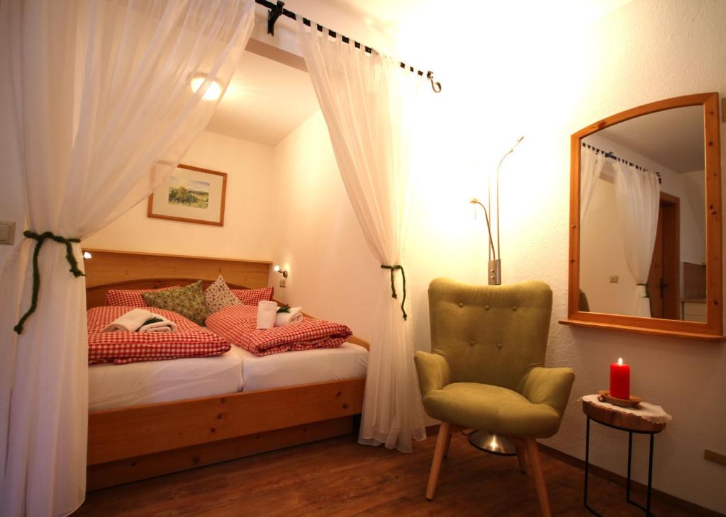 MühlenAlmDorf Tonnerhütte的一间卧室配有一张床、一把椅子和镜子