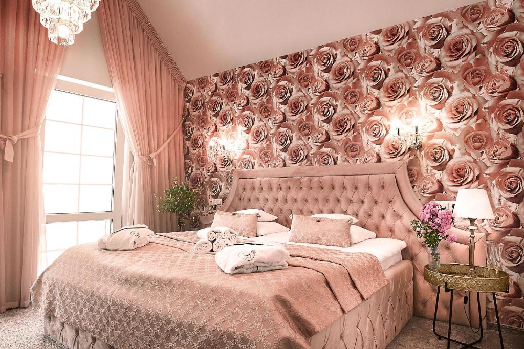 米科瓦伊基La Rose Residence的一间卧室设有一张大床,墙壁上覆盖着玫瑰花