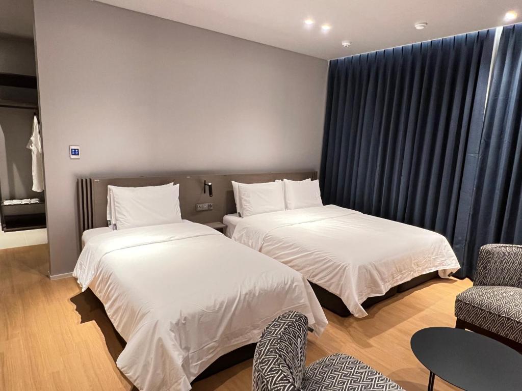 昌原市Jinhae Intercity Hotel的一间卧室配有两张床、一把椅子和一张沙发