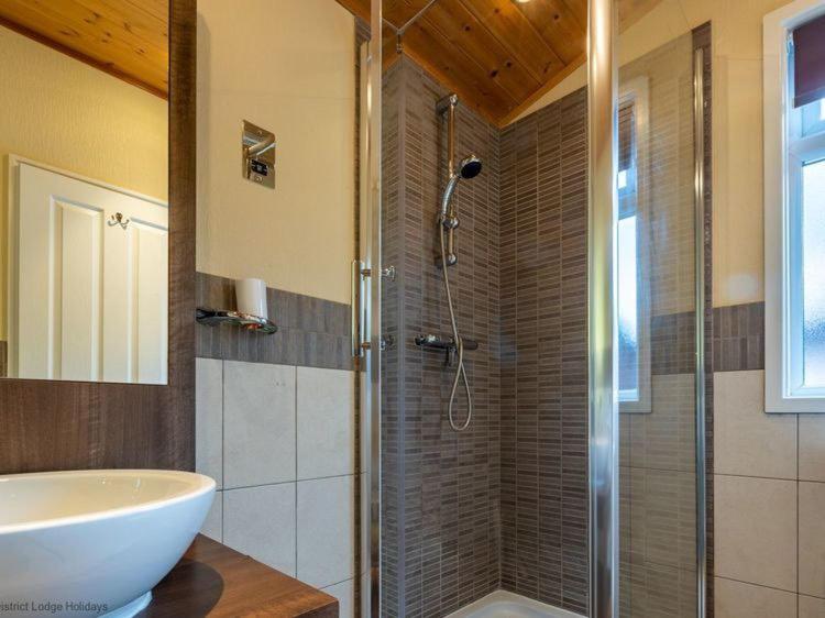 温德米尔Windermere Retreat - White Cross Bay Holiday Park的带淋浴、水槽和浴缸的浴室