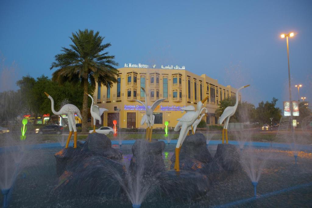 艾恩Al Massa Plus Hotel的一座建筑物前的喷泉,上面有白色鸟