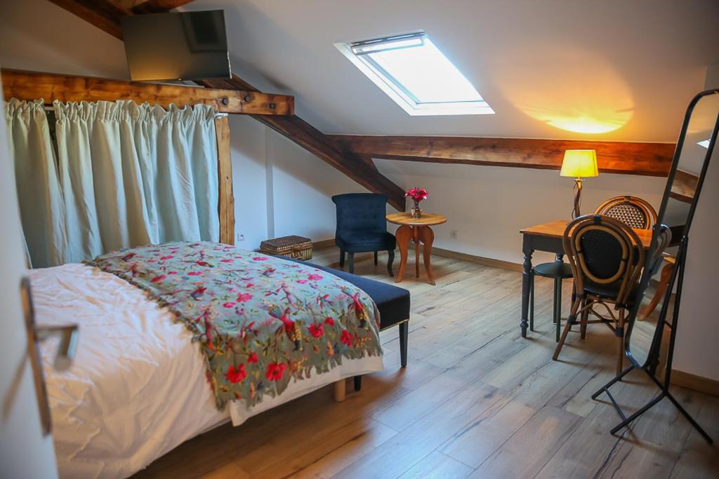 Tournan-en-BrieCROIX BLANCHE - LE LOGIS的一间卧室配有一张床和一张桌子及椅子