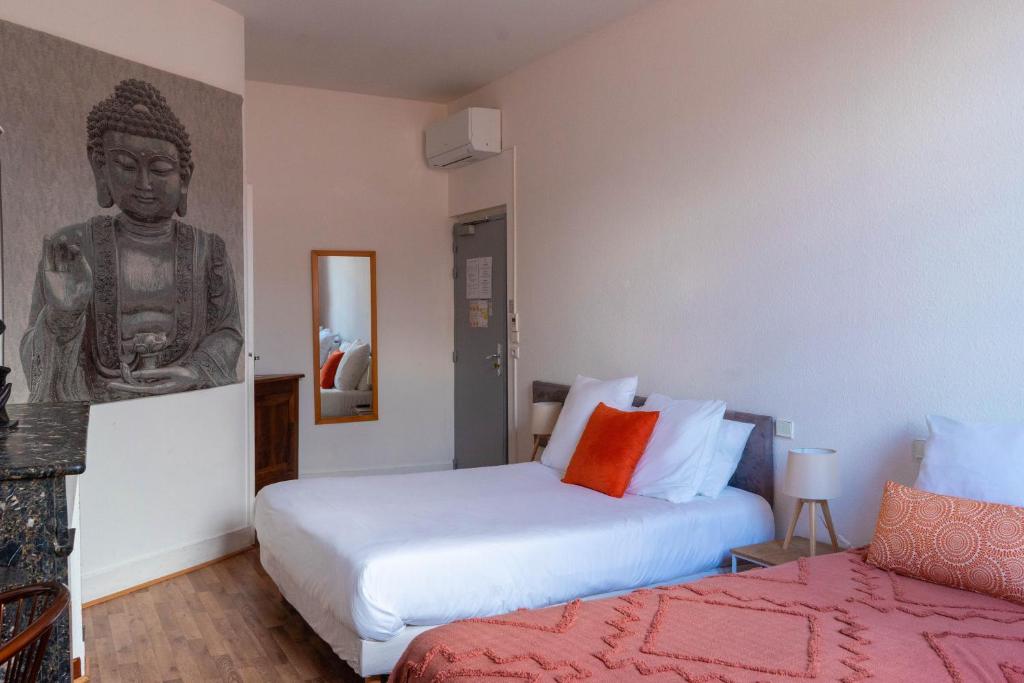 图卢兹库瓦巴拉农酒店的一间卧室设有两张床,墙上设有雕像