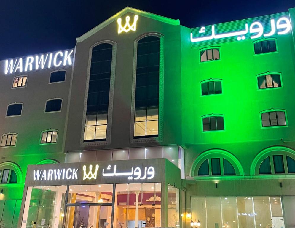 奥朱贝尔Warwick Al Jubail Hotel的绿色建筑的侧面有标志