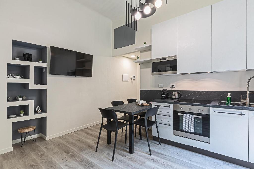 米兰La Boutique Milano: appartamento in Porta Romana的厨房配有白色橱柜和桌椅