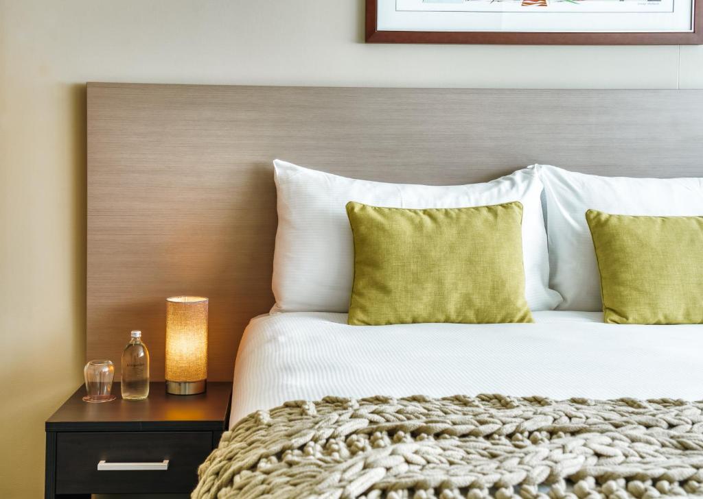 布里斯班The Point Brisbane Hotel的一间卧室配有一张带黄色枕头的大床