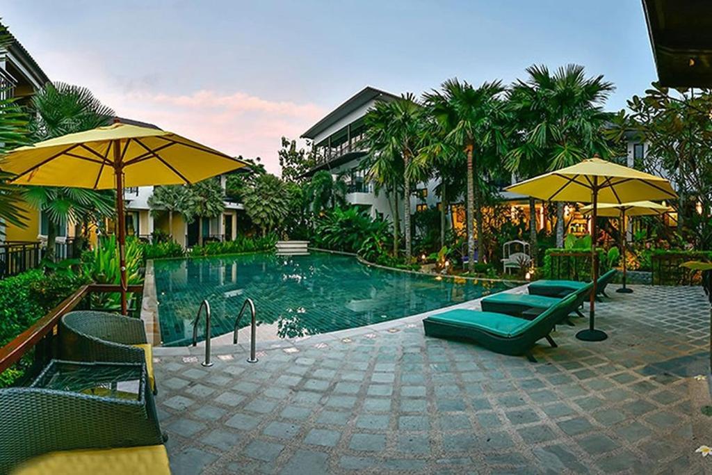 查龙Coco Retreat Phuket Resort and Spa - SHA Plus的度假村内带椅子和遮阳伞的游泳池