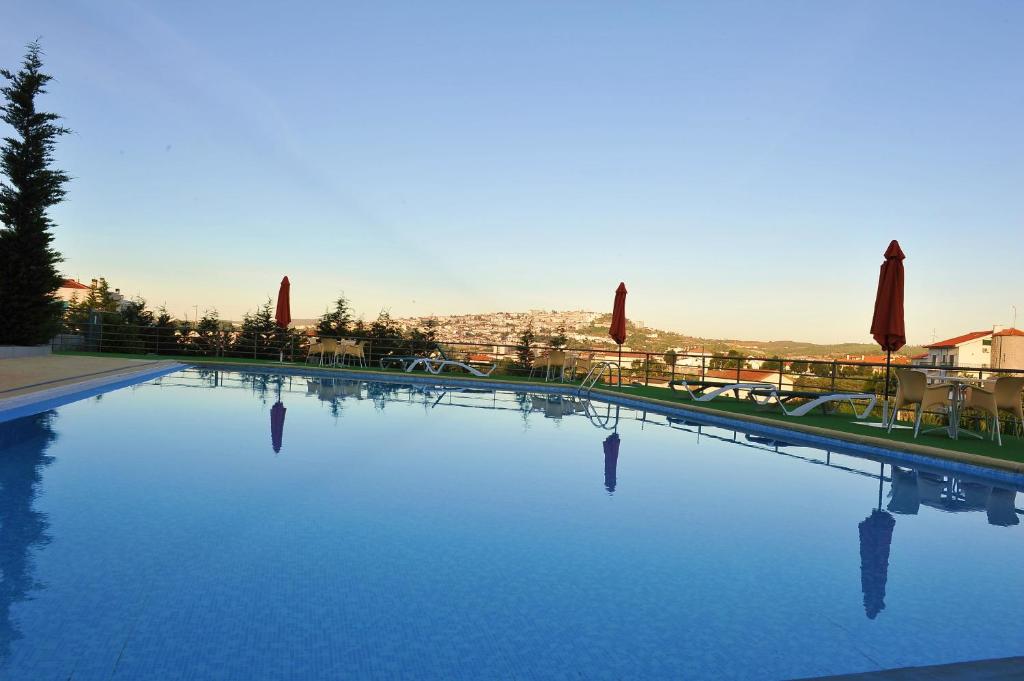 瓜尔达路西塔尼亚会议及水疗中心酒店的一座带蓝色水和遮阳伞的大型游泳池