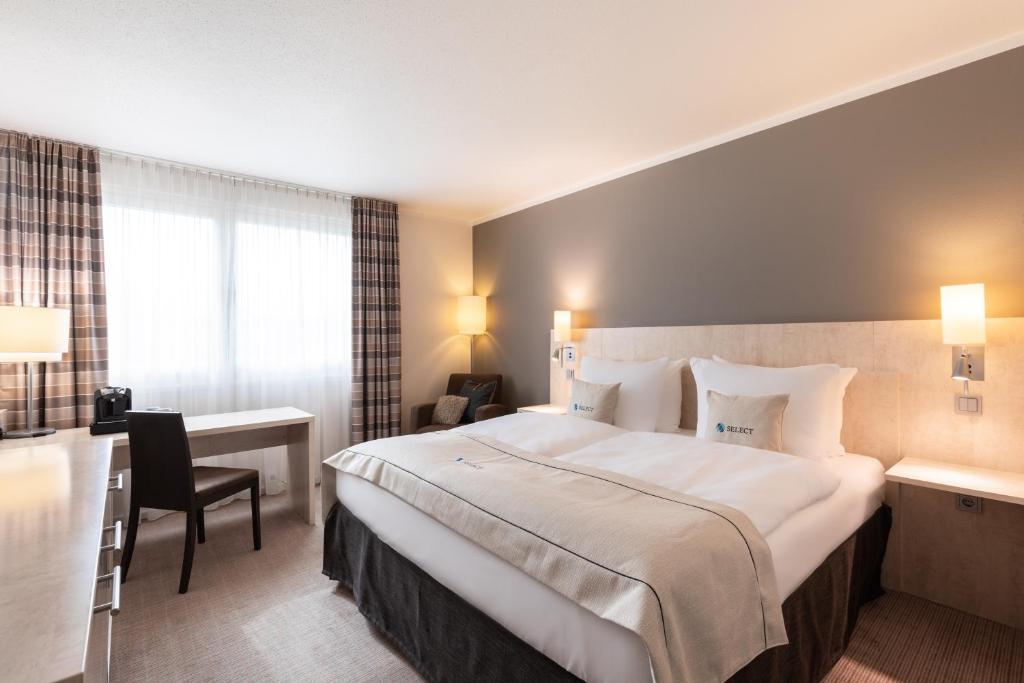 美因茨美因茨精选酒店的酒店客房设有一张大床和一张书桌。