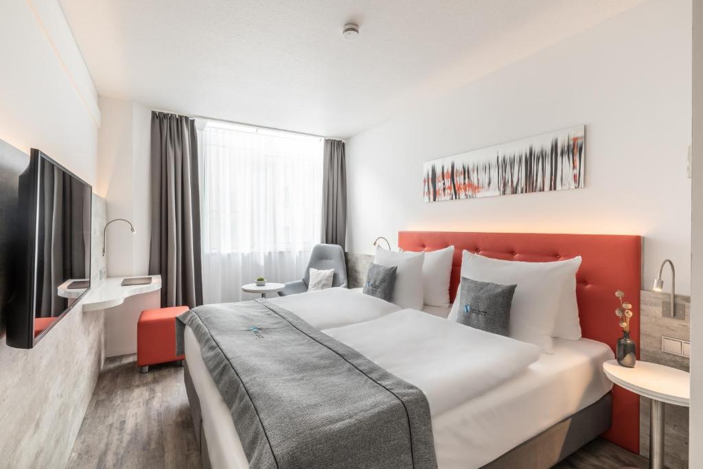 威斯巴登Select Hotel Wiesbaden City的酒店客房设有一张大床和一张书桌。