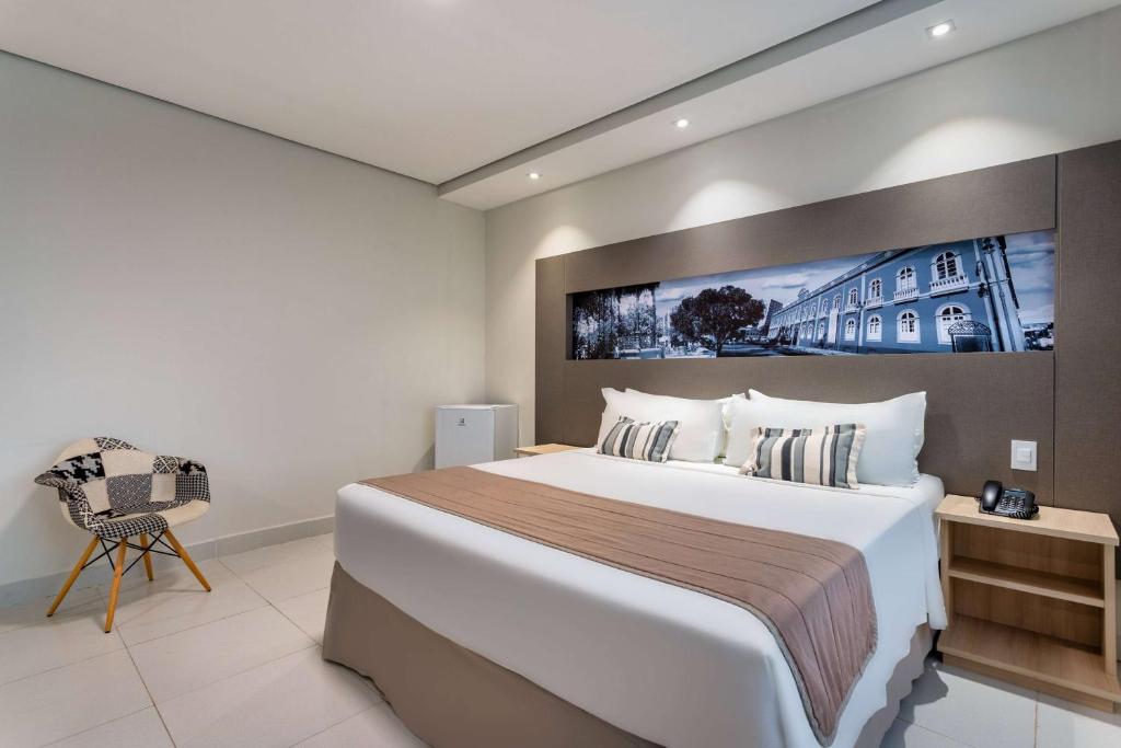 马瑙斯TRYP by Wyndham Manaus的酒店客房带一张大床和一把椅子