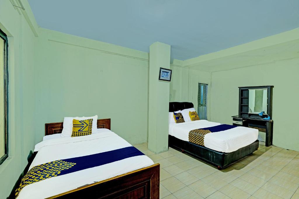 普兰巴南SPOT ON 91540 Ukuh Guesthouse的一间卧室配有两张床和镜子