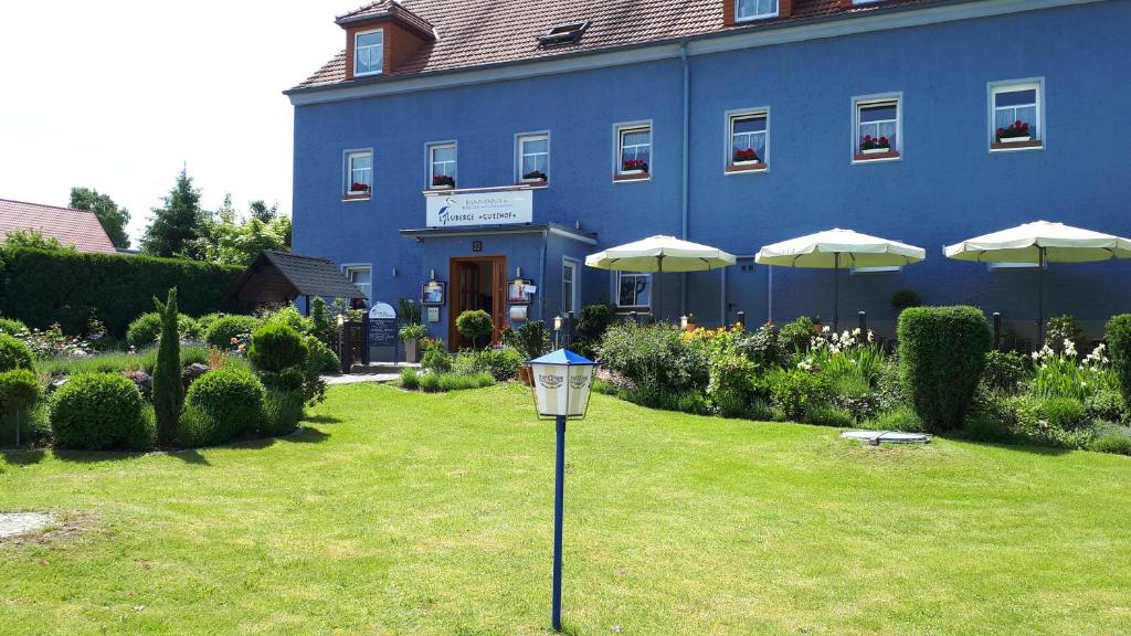 比绍夫斯韦尔达Logis L Auberge Gutshof的蓝色的建筑,有雨伞和草地上的灯光