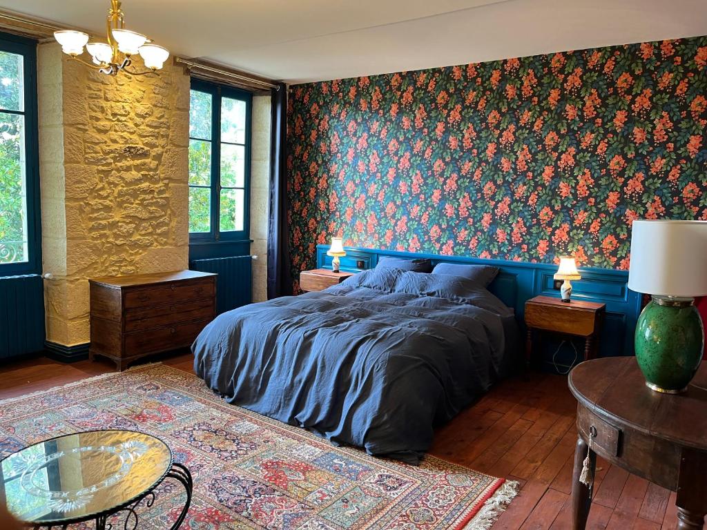 蒙蒂尼亚克Le Clos Chalmon Chambre d'hôte的一间卧室设有一张床和花卉墙