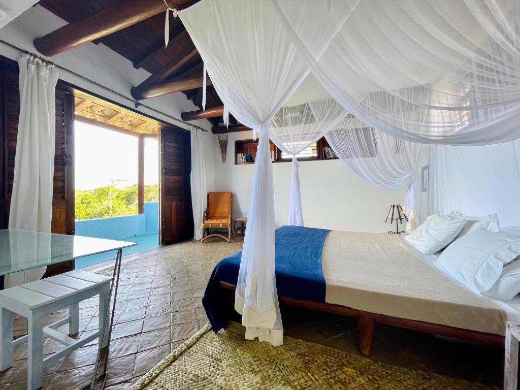 普拉亚埃斯佩洛Espelho Bahia Blue House的一间卧室配有一张带玻璃桌的天蓬床