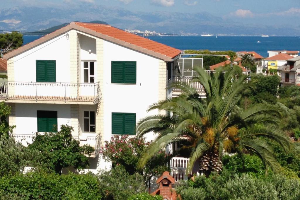 斯拉汀Apartments by the sea Slatine, Ciovo - 6061的白色的房子,有绿色百叶窗和棕榈树