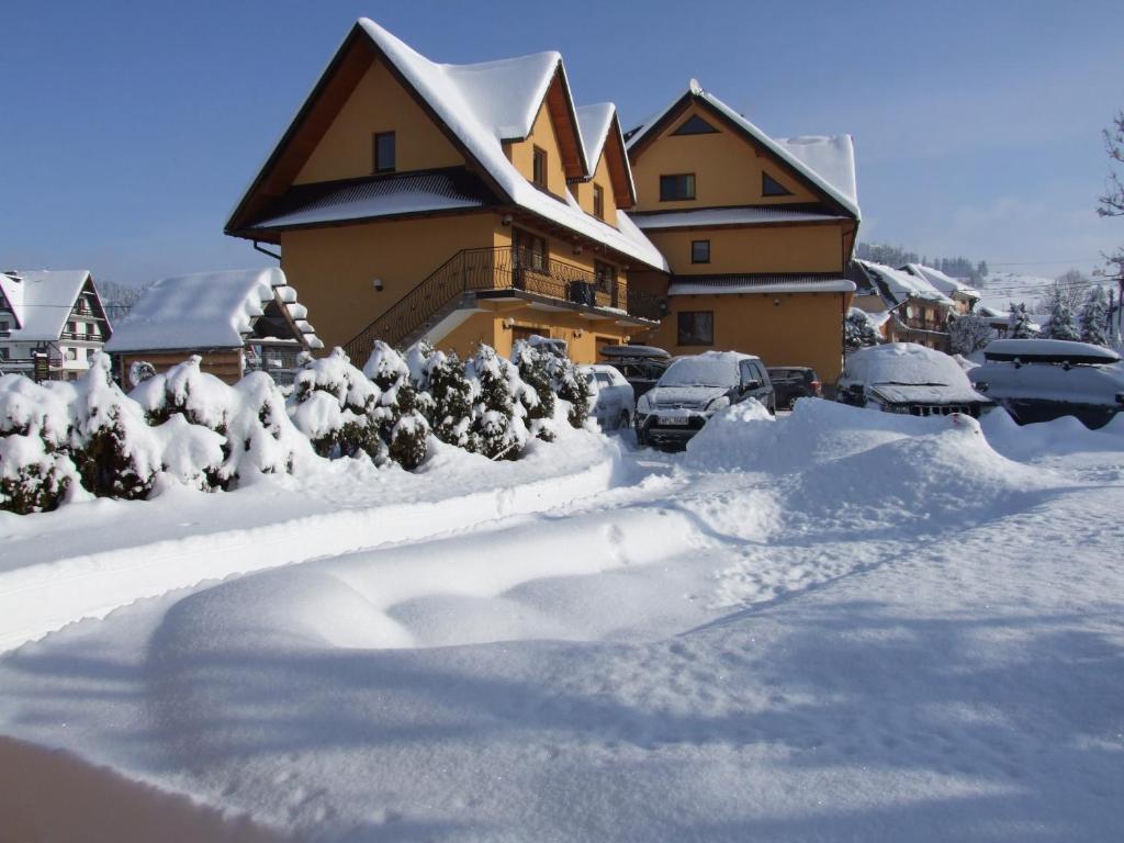 恰萨纳格拉Wynajem Pokoi ,,Góry Tatry Wypoczynek "Paweł Kuczyński的雪覆盖的房子,里面停有汽车