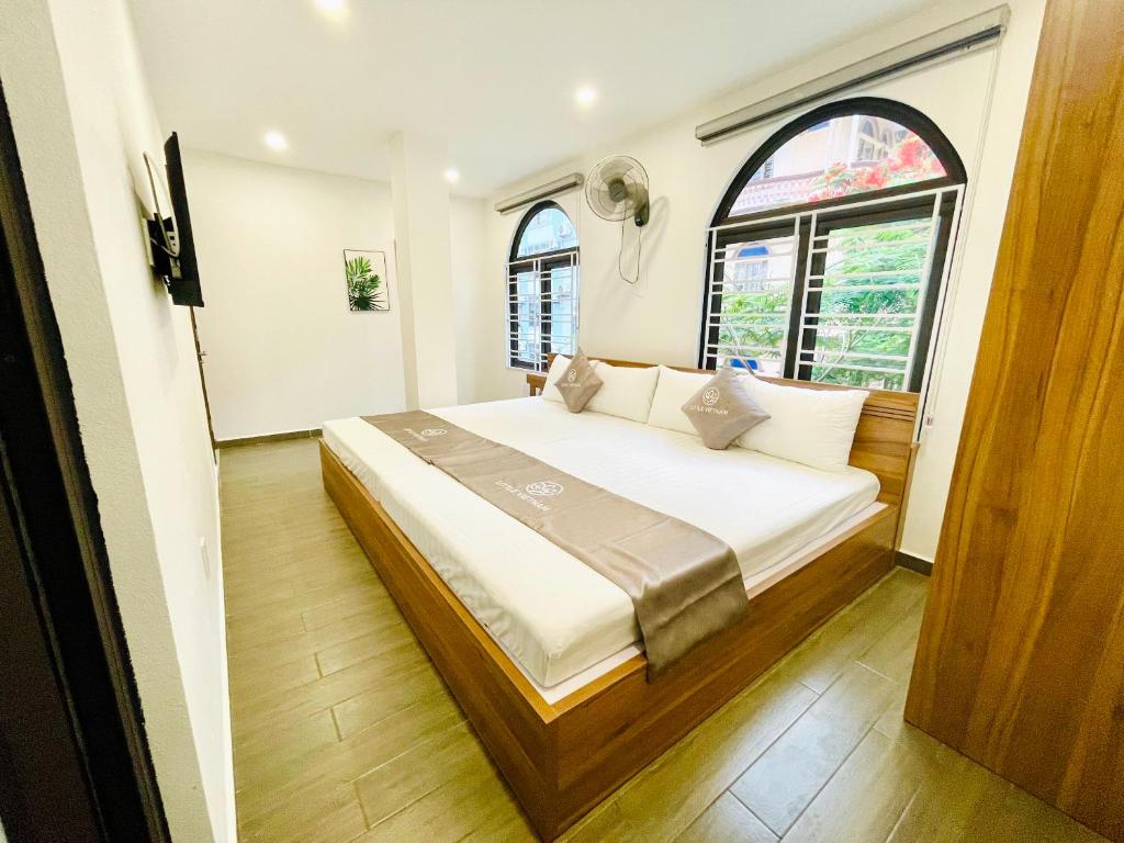 吉婆岛Little Vietnam Hotel - Cát Bà的一间卧室设有一张大床和两个窗户。