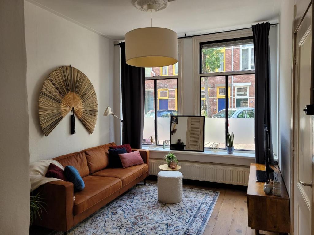 格罗宁根Characteristic ground floor apartment with box bed的客厅设有棕色的沙发和窗户。