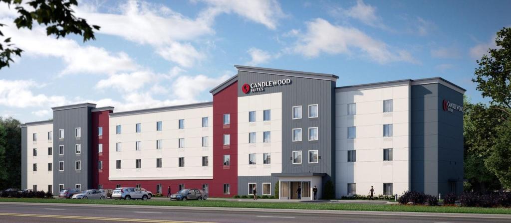 罗马琳达Candlewood Suites - Loma Linda - San Bernardino S, an IHG Hotel的一座白色和红色的大建筑,外面有汽车停放