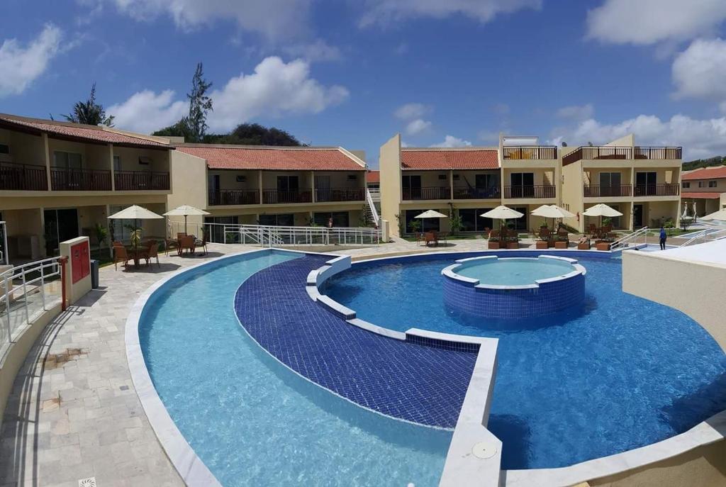 皮帕Solar Águas Pipa Prime的度假村的游泳池配有桌子和遮阳伞