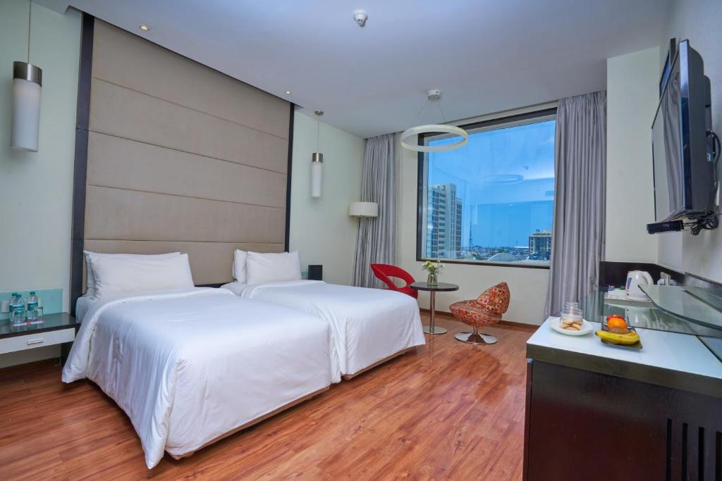 钦奈E酒店的酒店客房设有一张白色大床和一张书桌