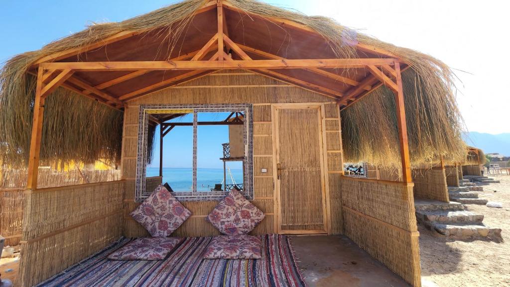 努韦巴Cinderella Camp Nuweiba的海滩上带茅草屋顶的小小屋