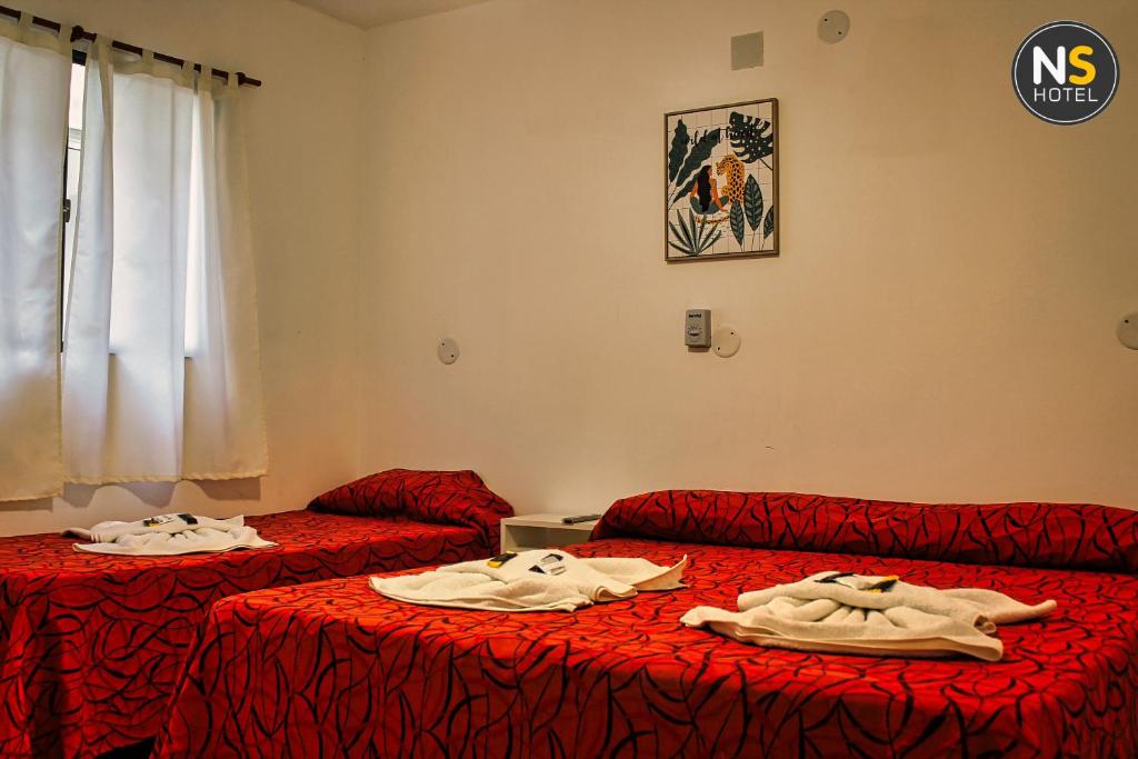 特尔马斯德里奥翁多Ns Hotel的红色床单的客房内的两张床