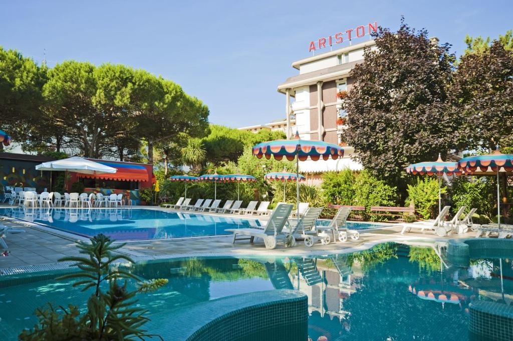 比比翁阿里斯顿酒店的一个带白色椅子的游泳池和一间酒店