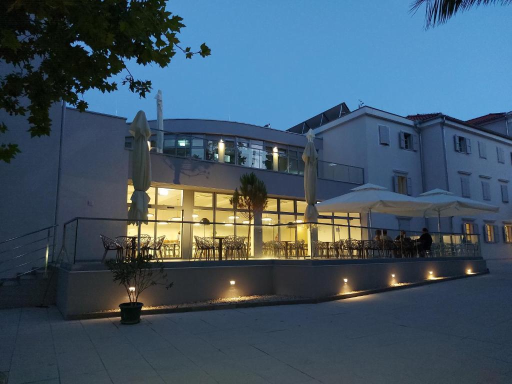 大洛希尼Hotel Villa Elisabeth - Veli Lošinj Health Resort的前面有桌子和伞的建筑