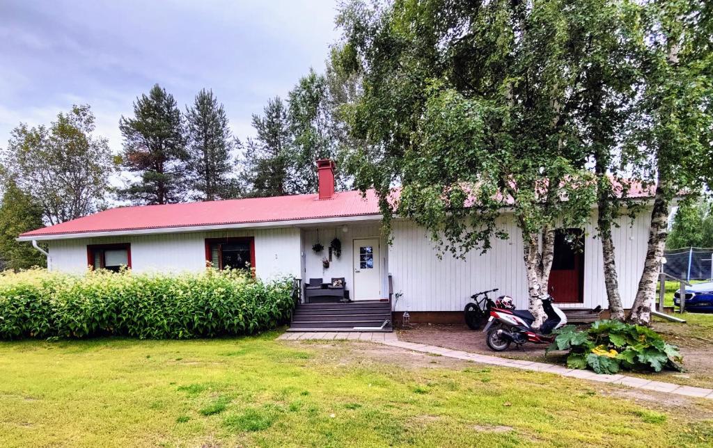 霍萨Holiday House Mäntyniemi的一座白色的房子,有红色的屋顶,前面停有一辆摩托车