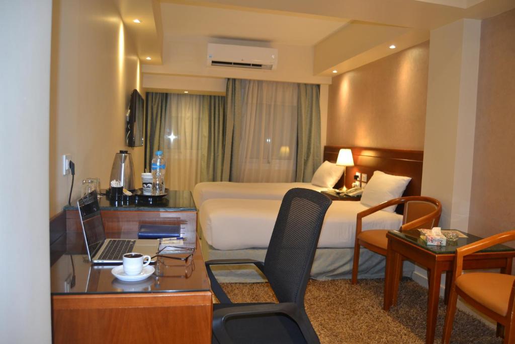 明亚Omar El Khayam Al Minya Hotel的酒店客房配有一张床、一张书桌和一台笔记本电脑