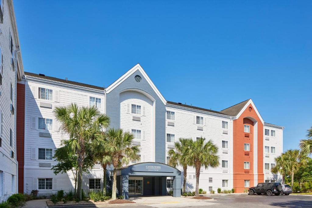 查尔斯顿Candlewood Suites Charleston-Northwoods, an IHG Hotel的一座白色的大建筑,前面有棕榈树